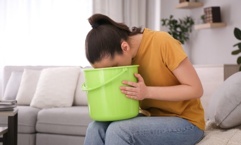 Person with nausea and vomiting holding their stomach