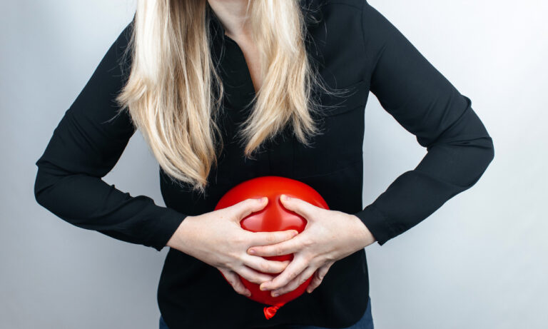 Woman holding her swollen stomach from excessive gas and bloating